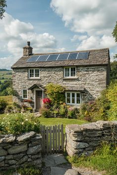 a stone house with a solar panel on the roof and windows, surrounded by greenery