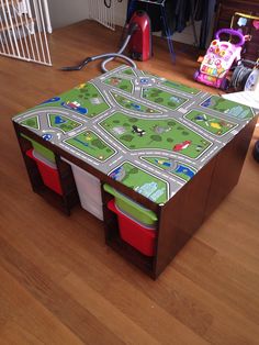 a child's play table with toy cars on it and storage bins underneath