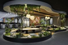 an office with plants and lights on the ceiling is pictured in this image, it appears to be designed as a circular seating area