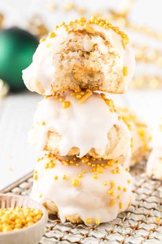 a stack of frosted donuts with sprinkles next to a bowl of gold flakes