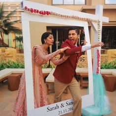 a man and woman standing in front of a photo frame