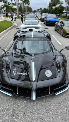 a black sports car parked on the side of the road with other cars behind it