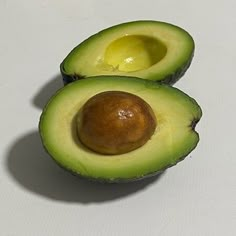 an avocado cut in half on a white surface