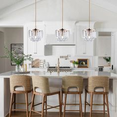 a kitchen island with four stools in front of it and lights hanging from the ceiling