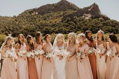 a group of women standing next to each other in front of a mountain with flowers