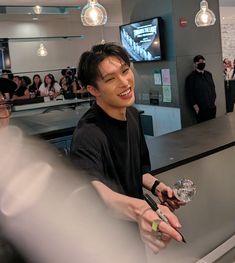 a man standing at a counter with a glass in his hand and people behind him