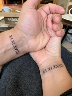 two people holding hands with roman numerals tattooed on their wrists and wristbands