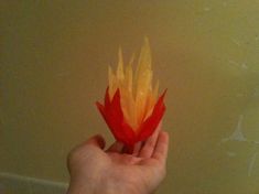 a person holding a flower in their left hand with yellow and red petals on it