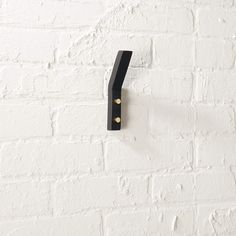 a black coat hook on a white brick wall