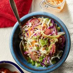 a blue bowl filled with salad next to another bowl full of vegetables and sauces