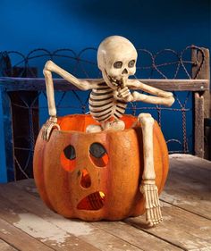 a skeleton sitting on top of a pumpkin