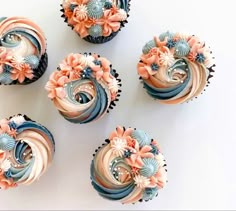 four cupcakes decorated with pink and blue frosting