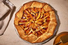 a pie sitting on top of a table next to a wooden spatula and cloth