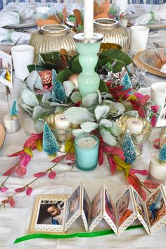 a table topped with pictures and candles on top of a white table cloth covered table