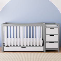 a baby's crib in a room with blue walls and white dressers