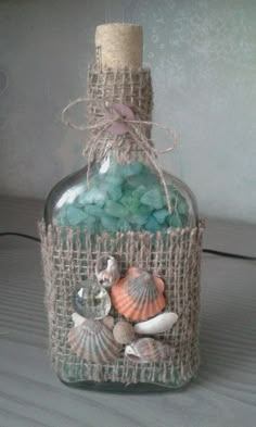 a bottle filled with sea shells on top of a table