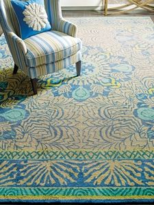 a blue and yellow area rug with an ornate design on the bottom, in front of a chair