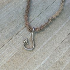 a necklace with a silver hook hanging from it's side on a wooden surface