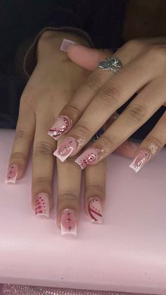 a woman's hand with pink and white nail designs on it, sitting next to a pink suitcase