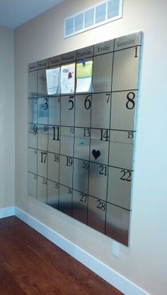 a wall mounted calendar in the corner of a room with wooden floors and white walls