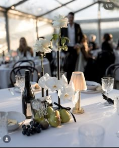 the table is set with flowers, fruit and wine for an elegant wedding reception in a tented area