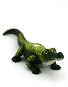 a small toy alligator sitting on top of a white surface