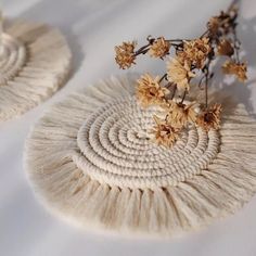 two white baskets with flowers in them on a tableclothed surface, one is made from yarn and the other is woven