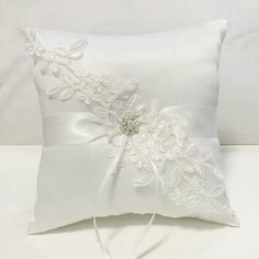 a white pillow with a flower and ribbon on the side, sitting on a bed