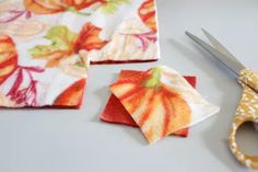 the scissors are next to two pieces of fabric that have been cut into flower designs