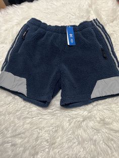 Upgrade your activewear collection with these Adidas Brandey Sherpa athletic sweat shorts in size XL, featuring a classic blue color and drawstring closure for a comfortable fit. These shorts are made of 73% polyester with a Sherpa fabric type, making them warm, soft, and moisture-wicking. Perfect for a variety of performance activities such as gym and training, track and field, soccer, basketball, and more, these shorts also have an 8-inch inseam and are lined for added comfort. Don't miss out on these high-quality shorts by Adidas, a trusted brand in sportswear. Adidas Sporty Bottoms With Built-in Shorts, Adidas Nylon Activewear, Adidas Activewear Sportswear, Adidas Relaxed Fit Moisture-wicking Bottoms, Sportswear Shorts With Functional Drawstring For Outdoor, Casual Adidas Sports Bottoms, Adidas Athleisure Nylon Activewear, Adidas Sports Nylon Shorts, Adidas Nylon Sports Shorts