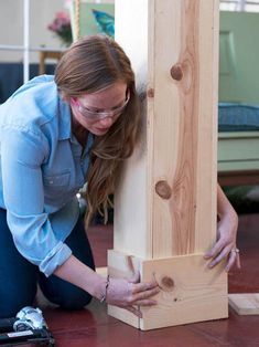 a woman kneeling down next to a piece of wood that has been built into it