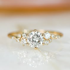 a close up view of a diamond ring on a white surface with gold trimmings