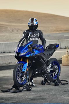 a man in black and blue riding on the back of a blue motorcycle with his helmet on