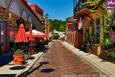 an empty street lined with tables and umbrellas