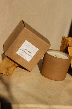 a candle sits on a table next to a box and some pieces of wood that have been cut in half