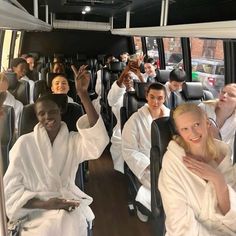 a group of people riding on the back of a bus with their hands in the air