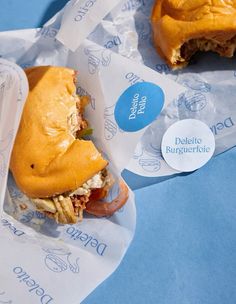 a half eaten sandwich sitting on top of plastic wrapper next to a blue background