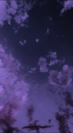 the night sky is filled with clouds and a half moon in the distance, as seen from ground level