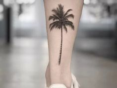 a small palm tree tattoo on the right leg, which is also in black and white