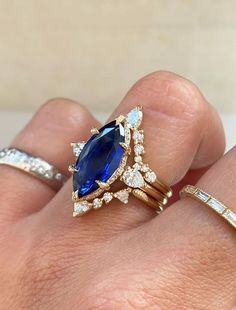 a woman's hand holding two rings with blue and white stones on them,