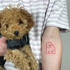 a person holding a dog with a small tattoo on their arm