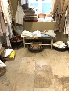 the inside of a clothing store with lots of clothes on display and folded towels in baskets