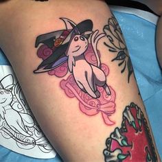 a woman's leg with a cat and witch hat tattoo on her left thigh