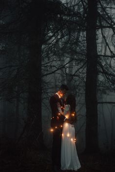 a bride and groom standing in the woods with fairy lights on their foreheads at night