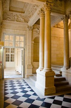 an ornate building with columns and checkered floor