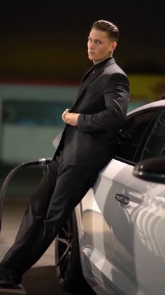 a man in a suit sitting on the hood of a car