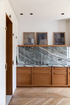 an empty kitchen with wooden cabinets and marble counter tops, along with wood flooring