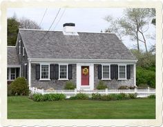 a small gray house with red door and shutters