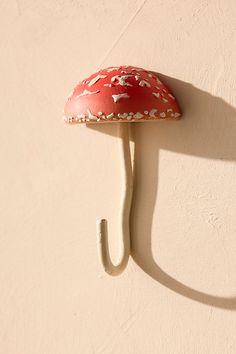 a red mushroom mounted to the side of a wall with a white hook on it