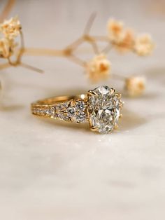 a close up of a diamond ring with flowers in the background